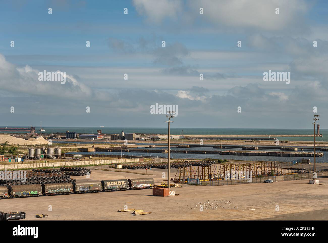 Europe, France, Dunkerque - July 9, 2022: Port scenery quay 6. Stored steel plate roles with train wagons nearby. Looking towards North Sea showing mo Stock Photo