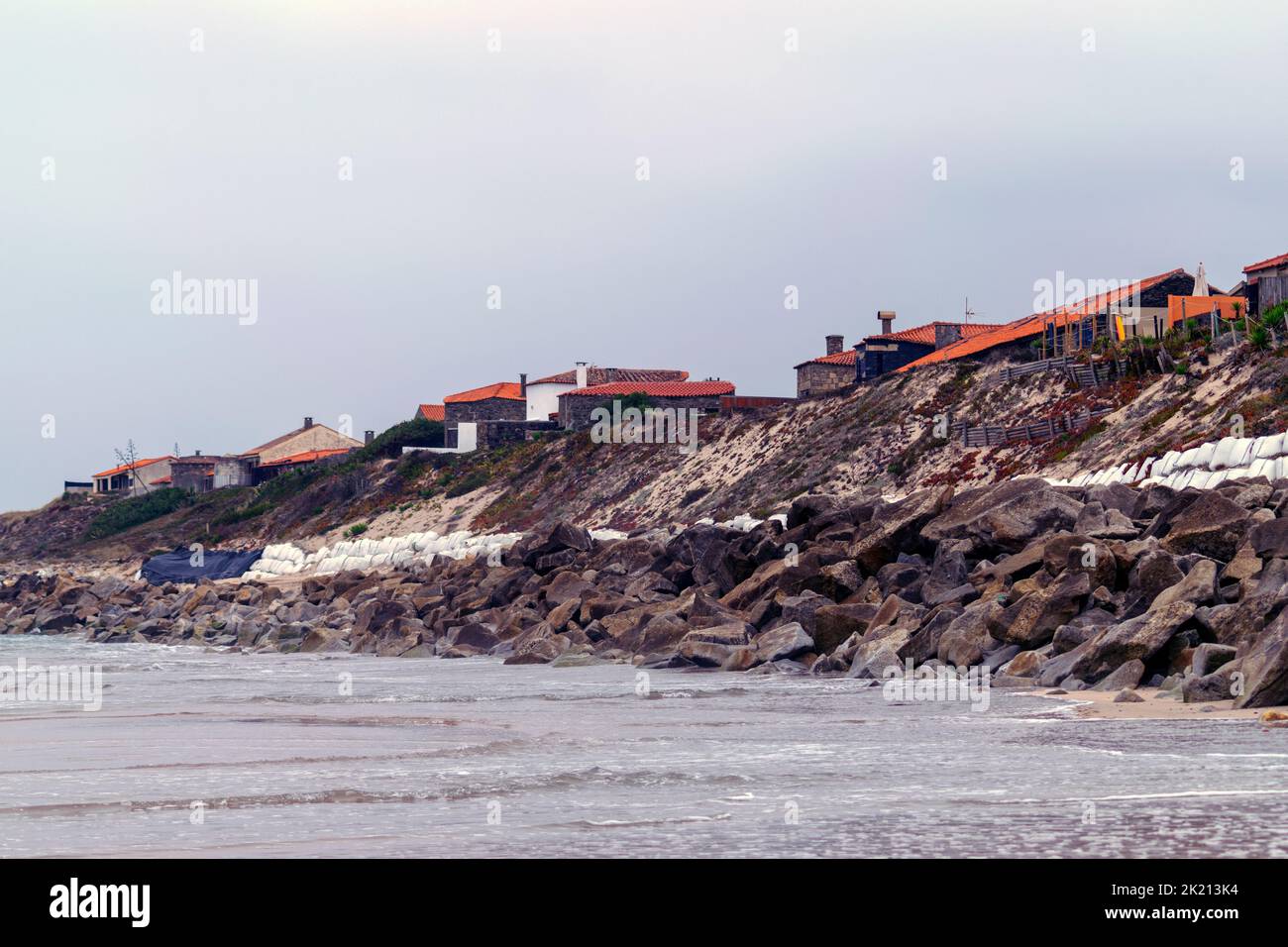 Beach coast living homes too close to the ocean break. Sand dunes and homes protected by big rocks or Boulders. Climate changes and ocean rising level. Stock Photo
