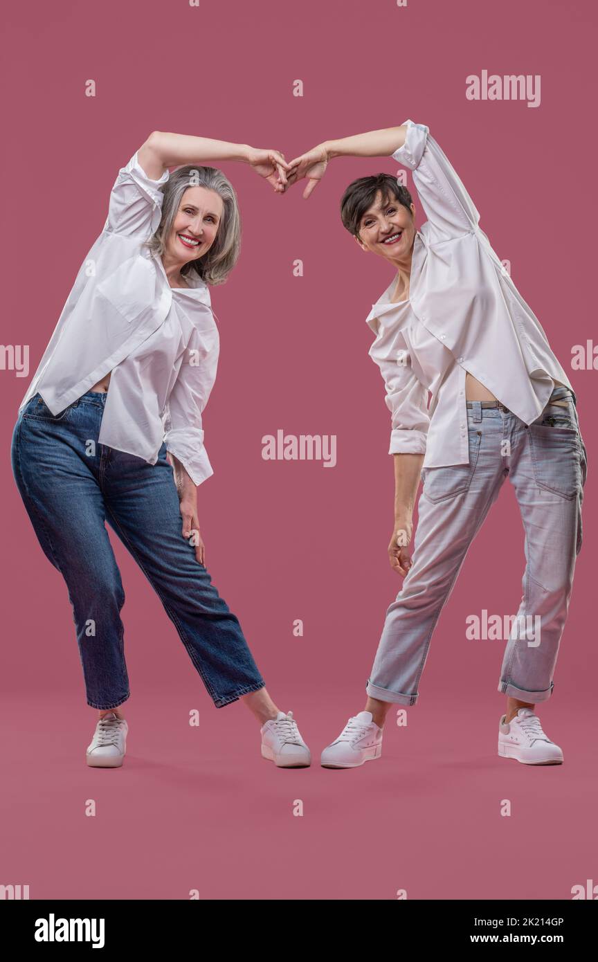 Women in white shirts smiling and showing love sign Stock Photo