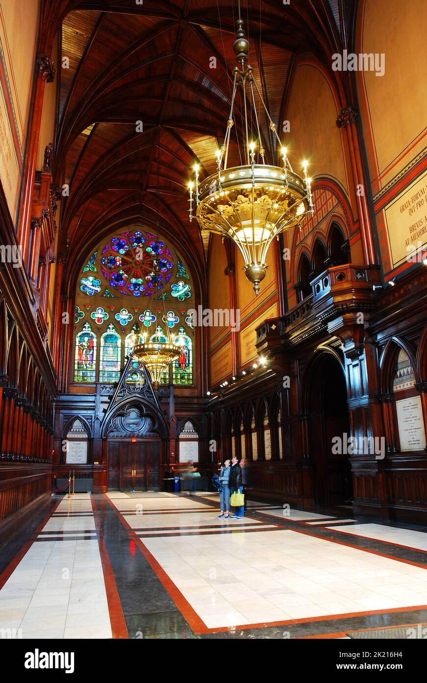 The Interior of Harvard University's Memorial Hal is designed in a Gothic style architecture with stained glass windows and a chandelier on campus Stock Photo