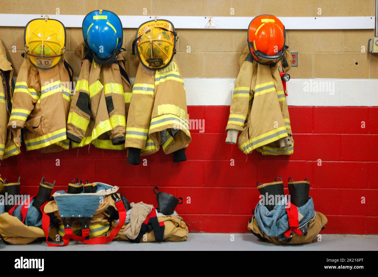 A fireman's equipment is hung and the jacket, boots and helmet placed  on the wall ready for the next fire emergency at a suburban fire department Stock Photo