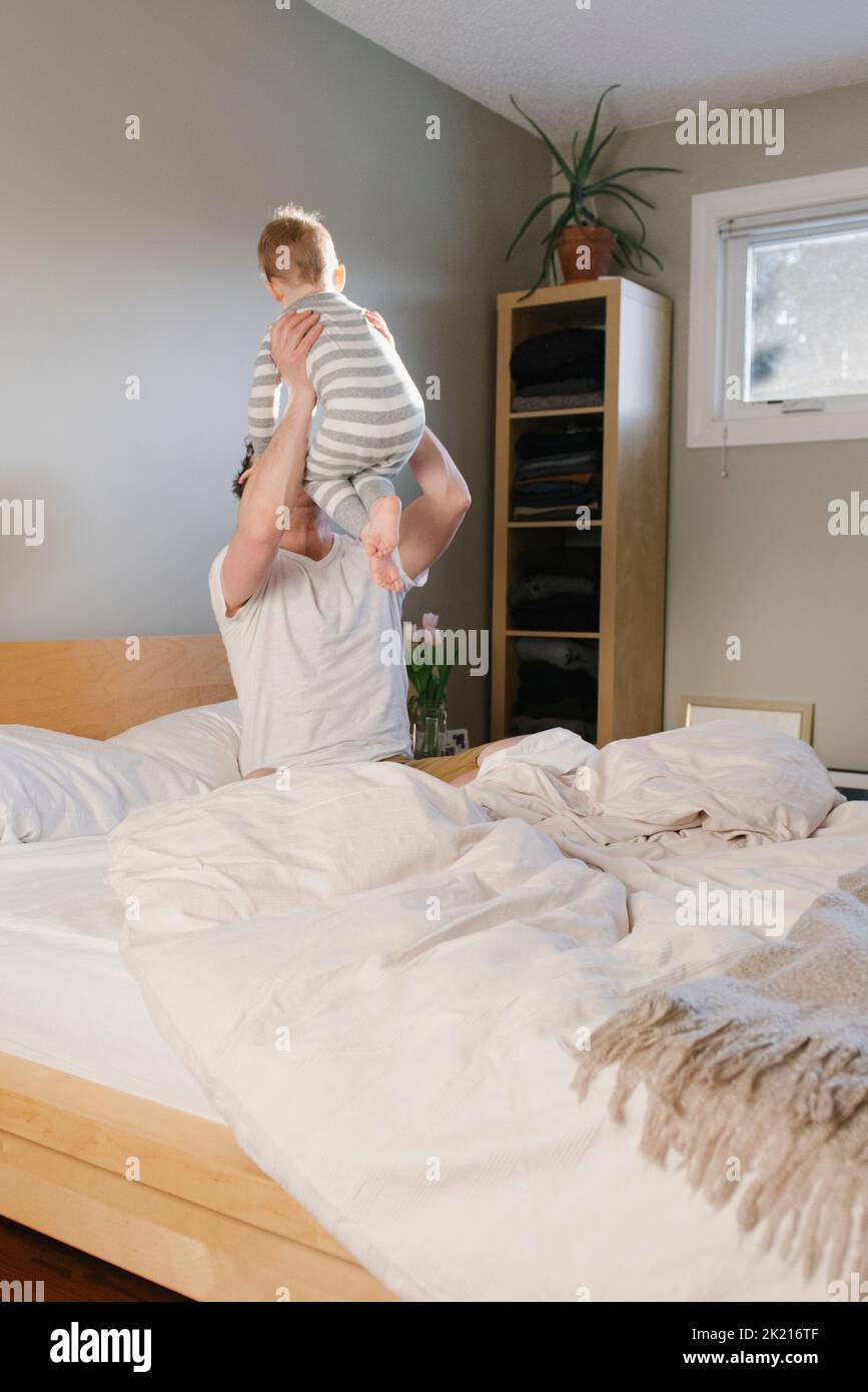Father lifting young son on bed Stock Photo Alamy