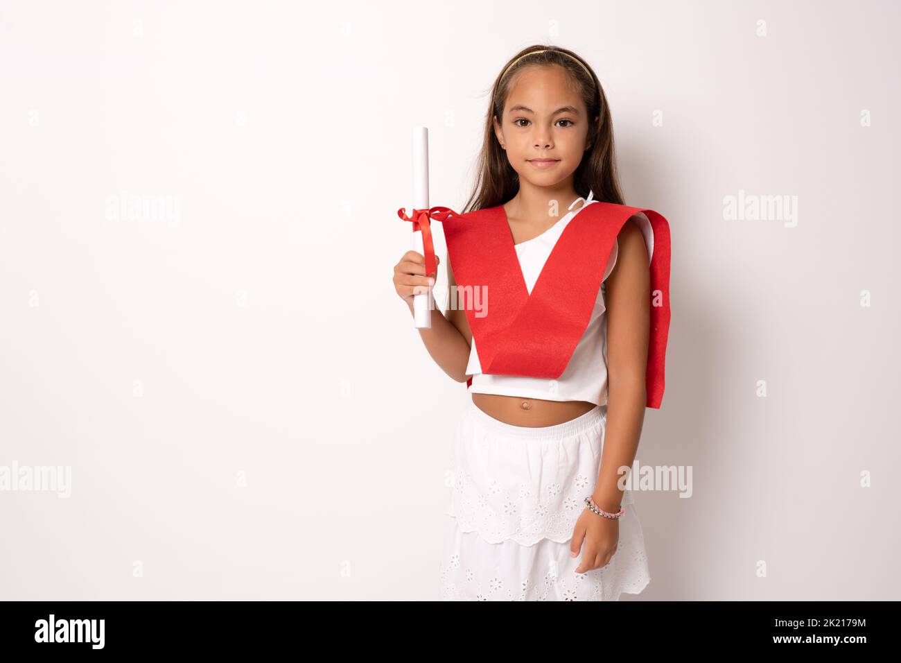 Little child girl wearing graduation ribbon and holding diploma in ...