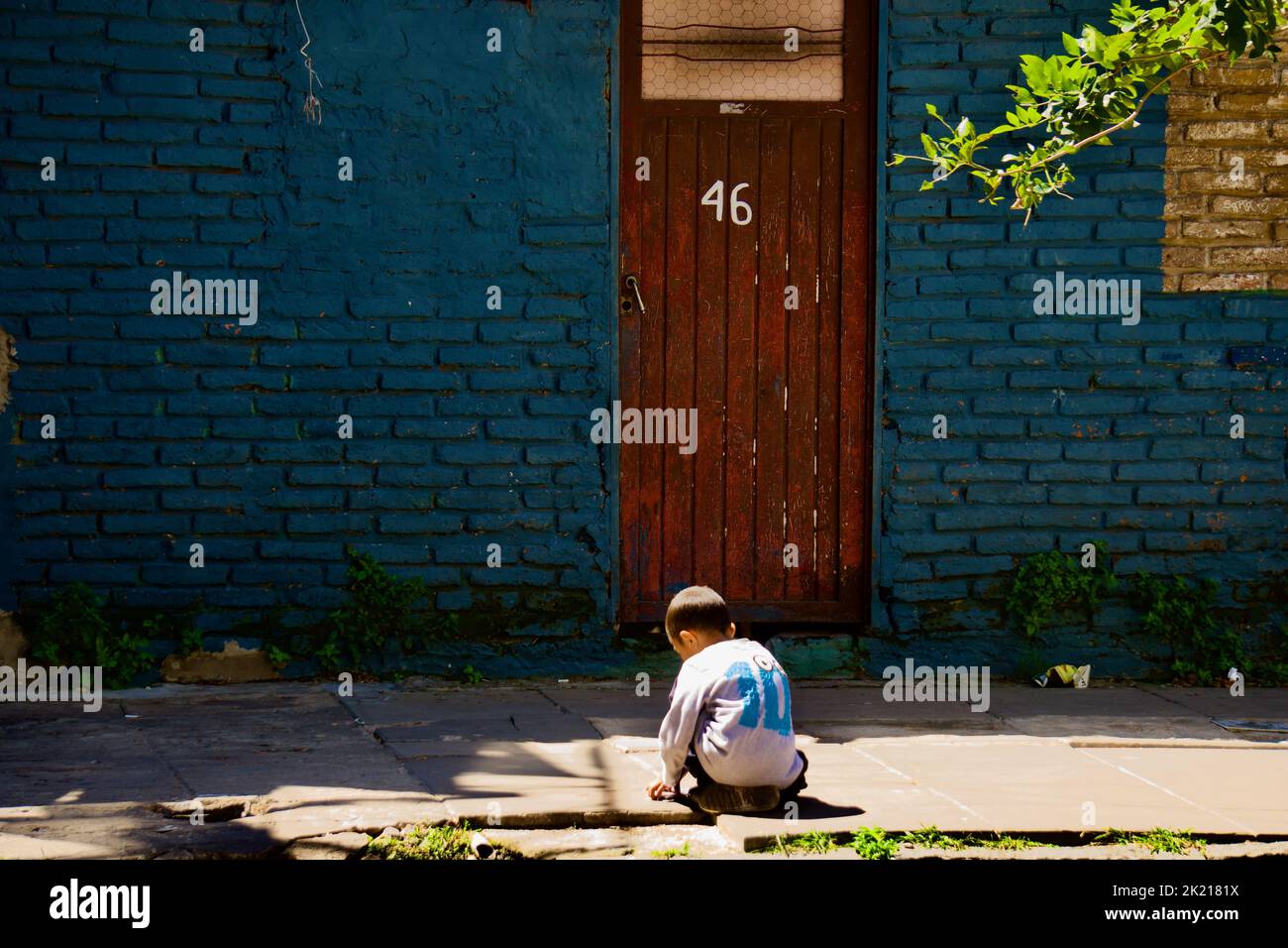 A view of a child playing in the garden at the wooden door with the number 46 Stock Photo