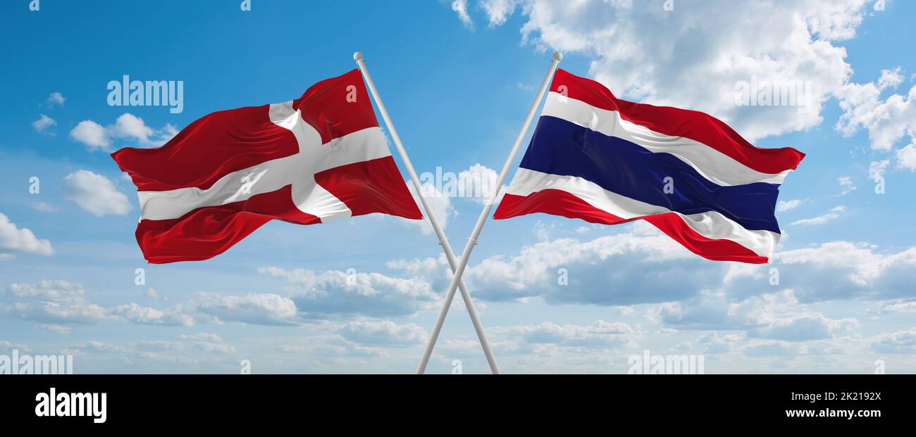 two crossed flags thailand and Denmark waving in wind at cloudy sky ...