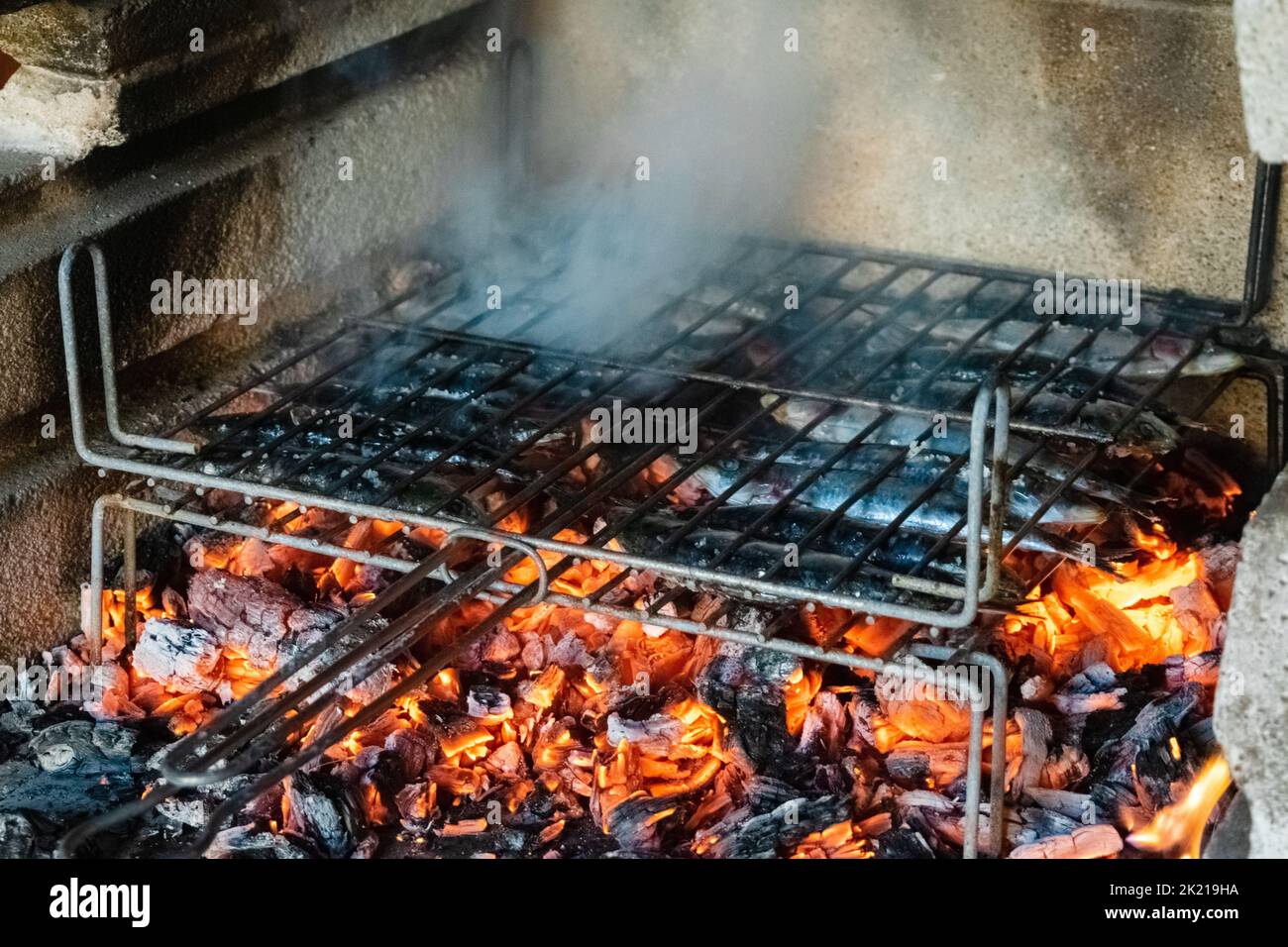 Grilling sardines over the barbecue fire Stock Photo