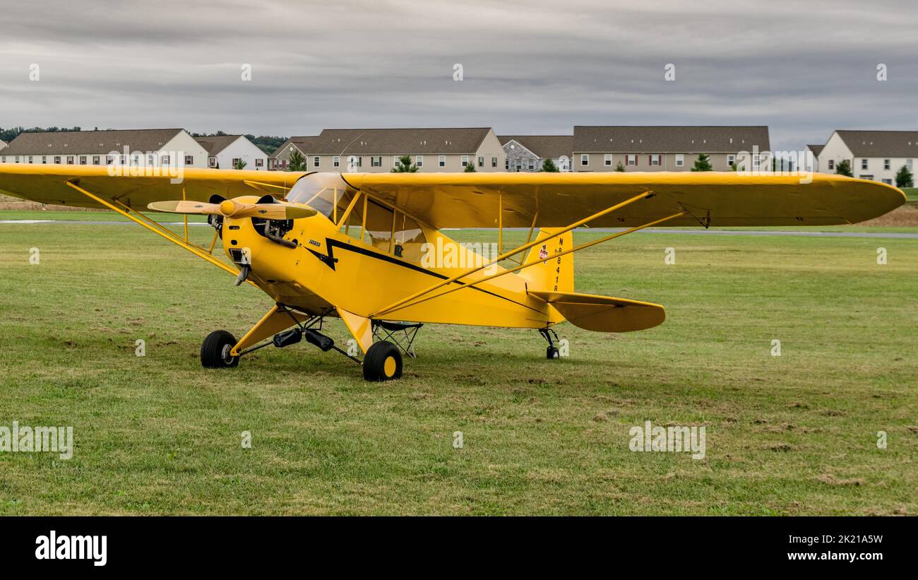 A closeup of a Piper Cub parked in the grassy landing spot Stock Photo