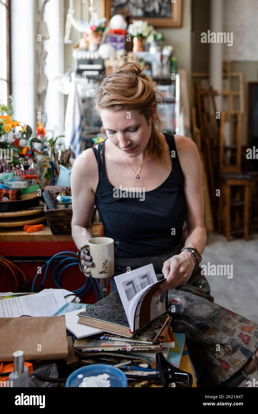 Female artist looking at art books in studio Stock Photo