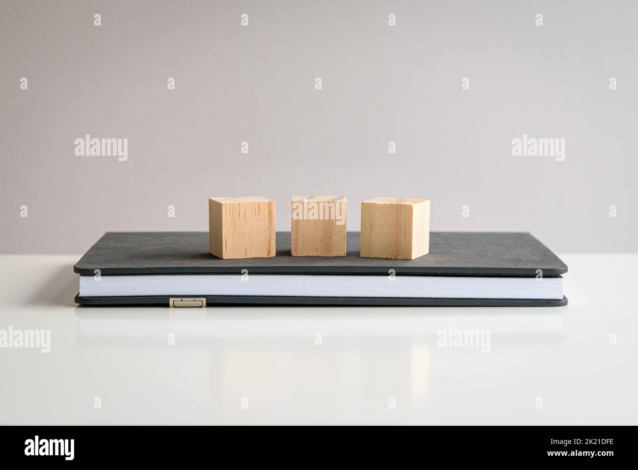 Three blank wooden block cubes on top of a notepad. Free text and