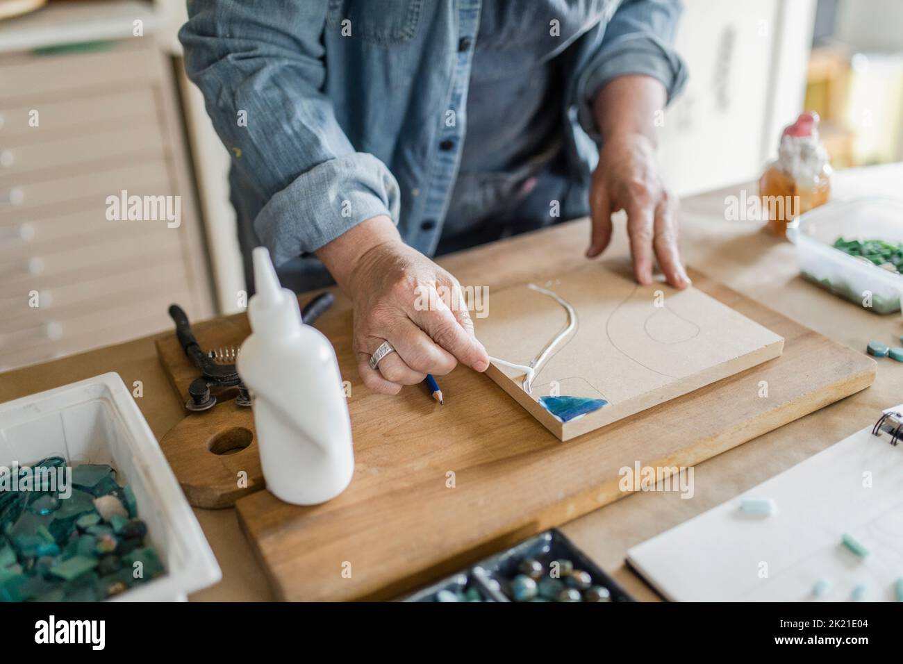 Female artist applying glue to board for mosaic project in art studio