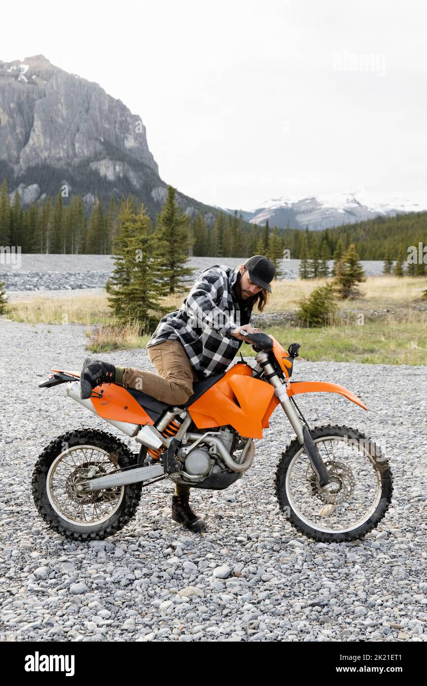 Man getting on dirt bike below remote mountain hires stock photography and images Alamy