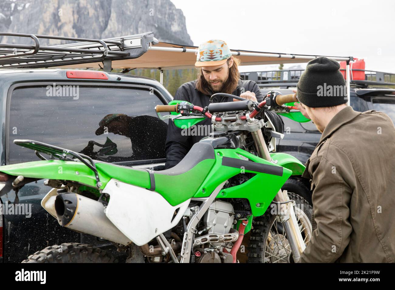 Brothers remove dirt bike from overland SUV Stock Photo