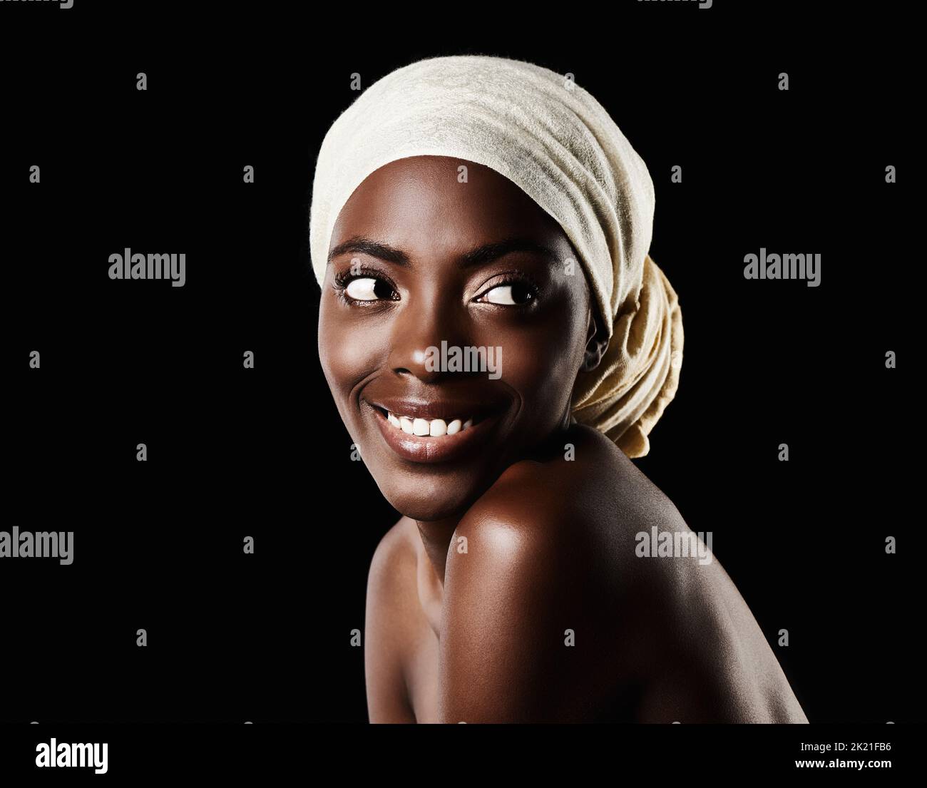 Beautiful skin. Studio portrait of a beautiful woman wearing a headscarf against a black background. Stock Photo