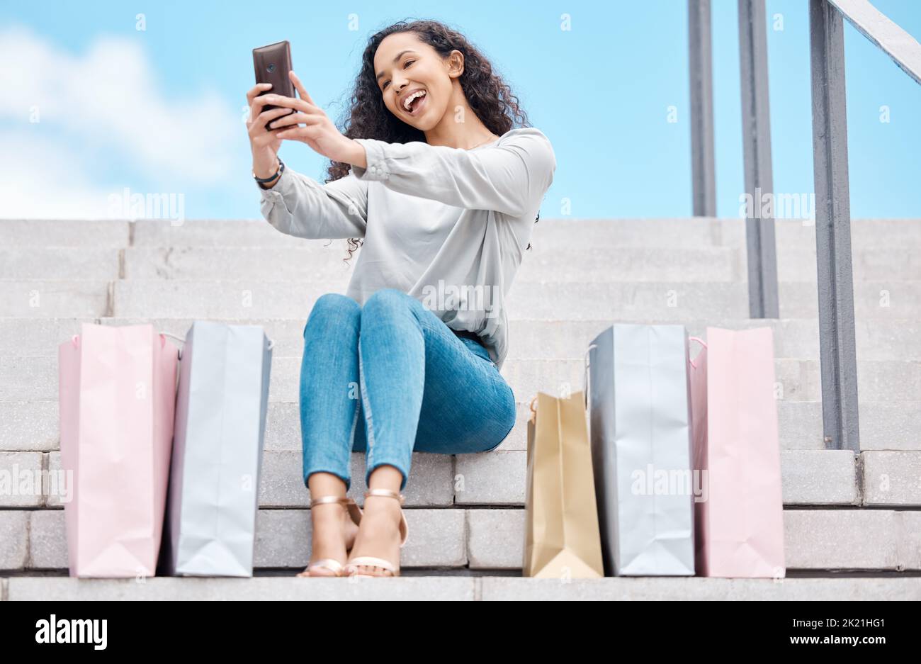 Selfie, shopping and female influencer and blogger sitting outside with bags after a spending spree while on city stairs. Happy, consumer or customer Stock Photo