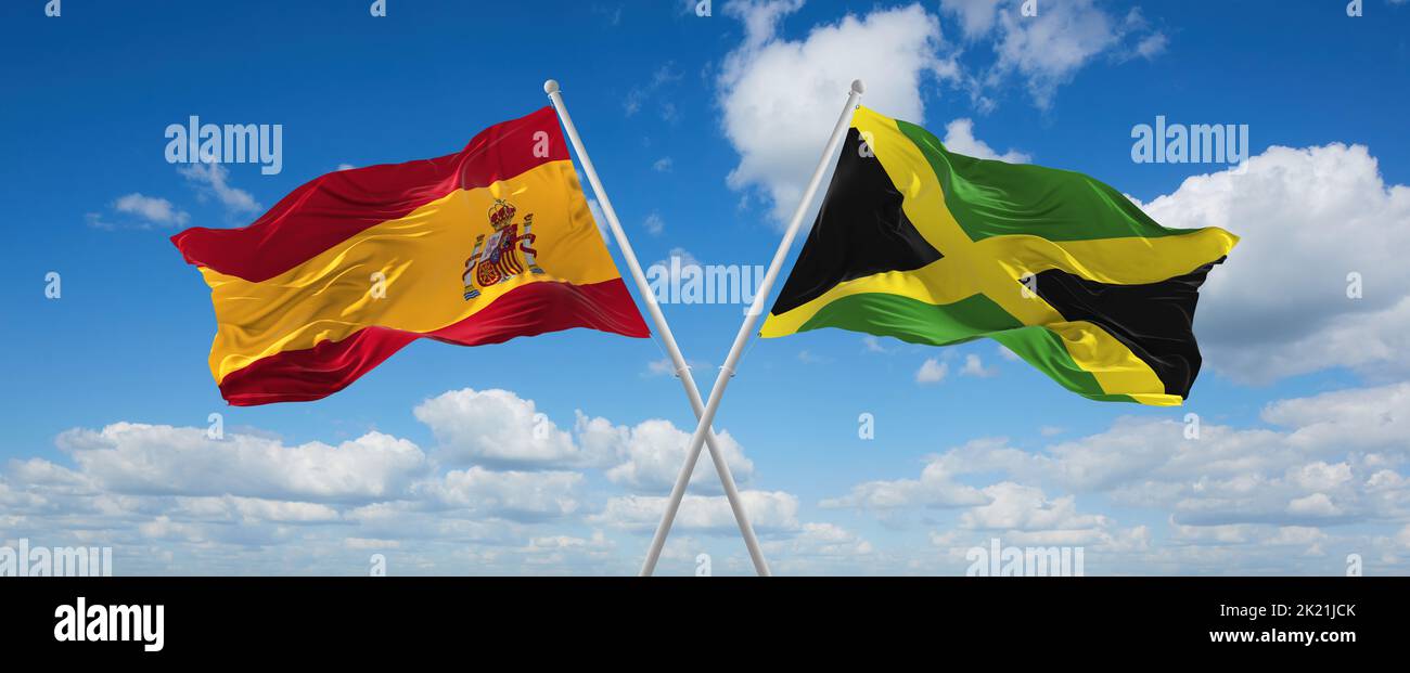 two crossed flags Jamaica and spain waving in wind at cloudy sky