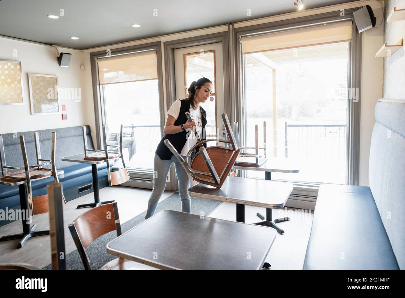 Female business owner removing chair from table in cafe Stock Photo Alamy