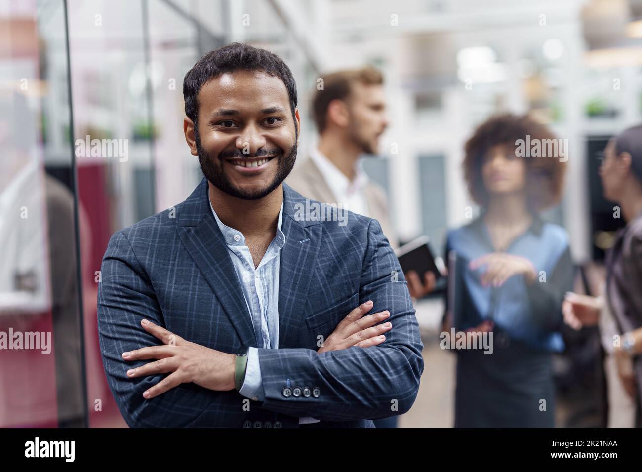 Portrait of indian businessman standing in modern office on colleagues background Stock Photo