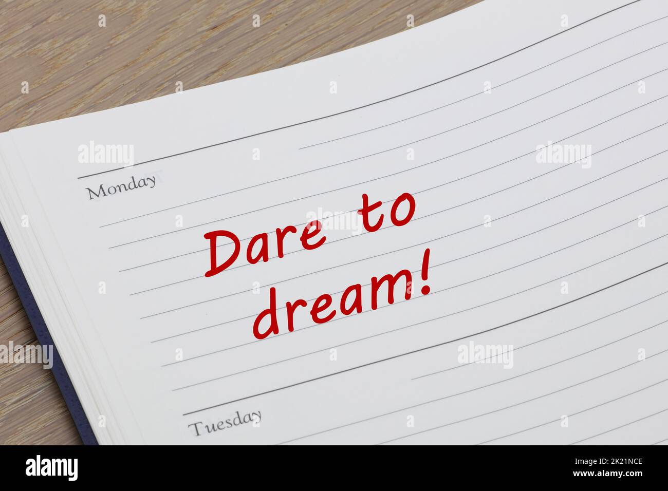 Dare to dream diary reminder message open on desk Stock Photo
