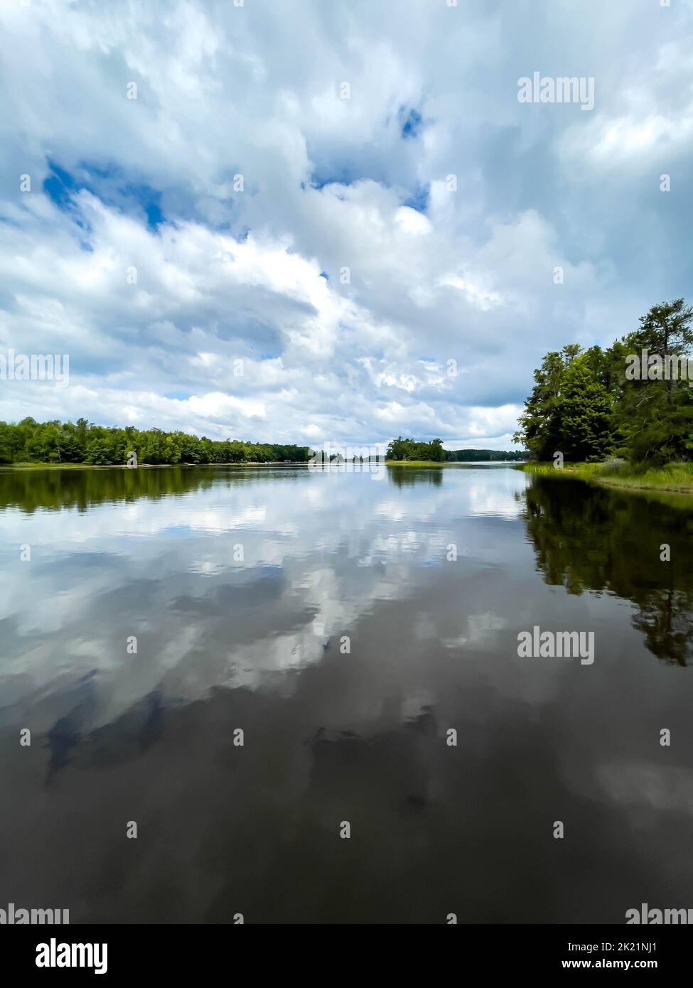 Lake Nokomis, Tomahawk, Wisconsin, lake reflecting clouds on a calm summer day, vertical Stock Photo