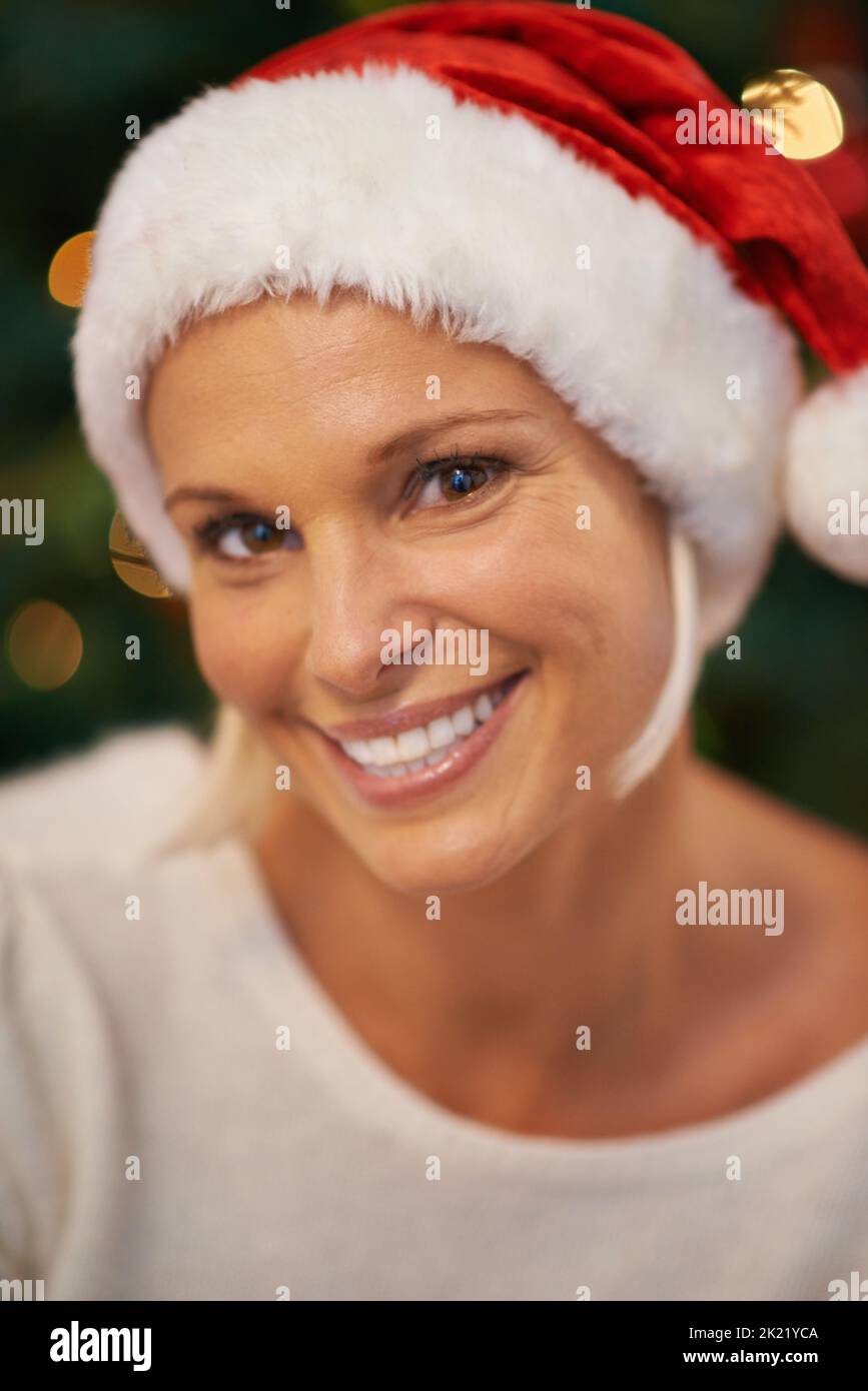 Shes definitely not on the naughty list. a cheerful young woman wearing a christmas hat. Stock Photo