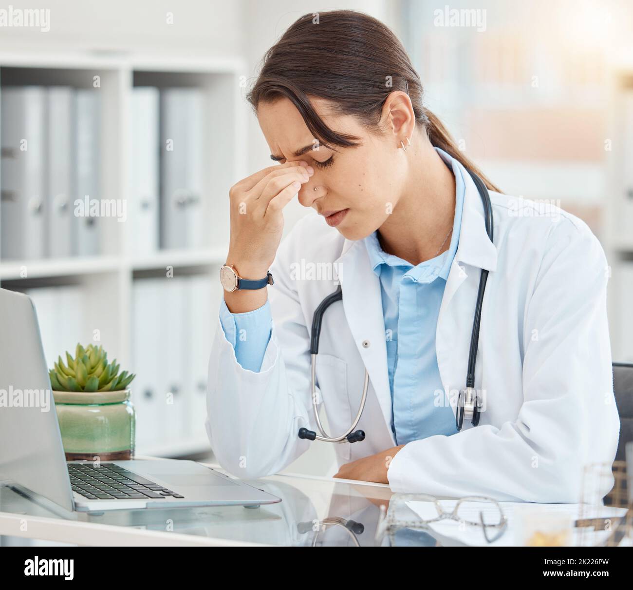 Stress, depression and tired female doctor suffering from a headache or mental health while sitting in an office with laptop. Frustrated, upset and Stock Photo