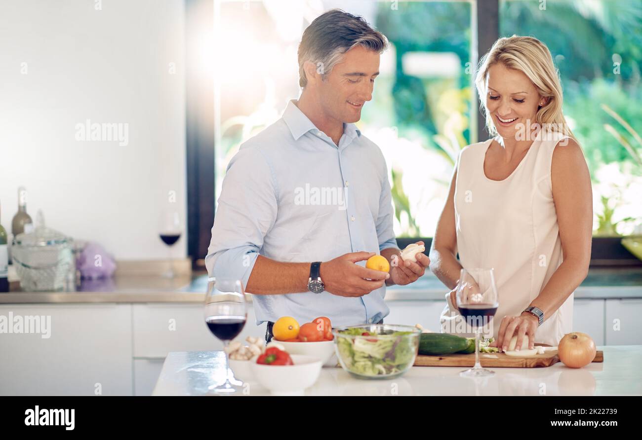 Cooking is a great way to bond. an affectionate mature couple talking while making dinner together. Stock Photo