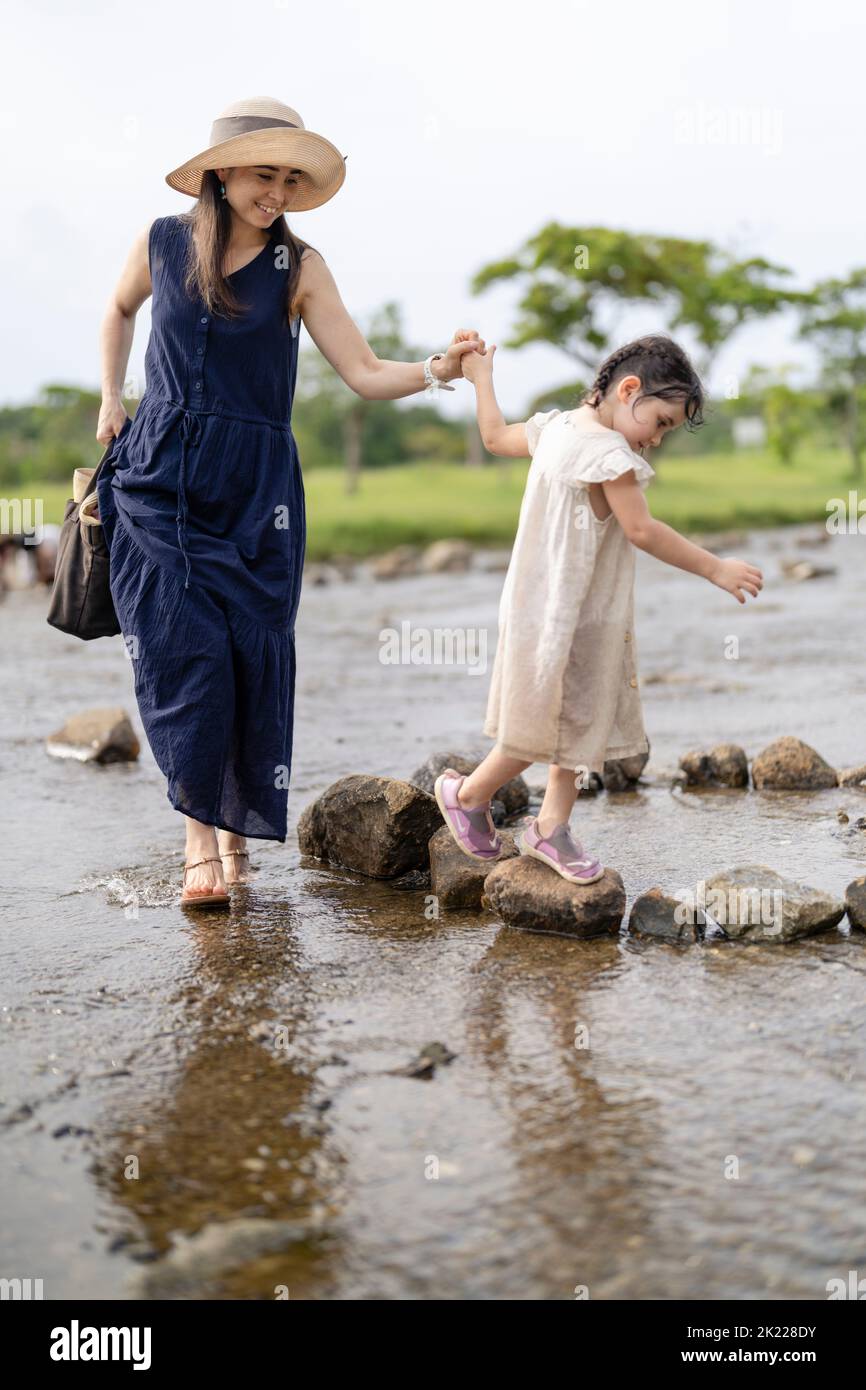 Young girl on stepping stones with mother Stock Photo