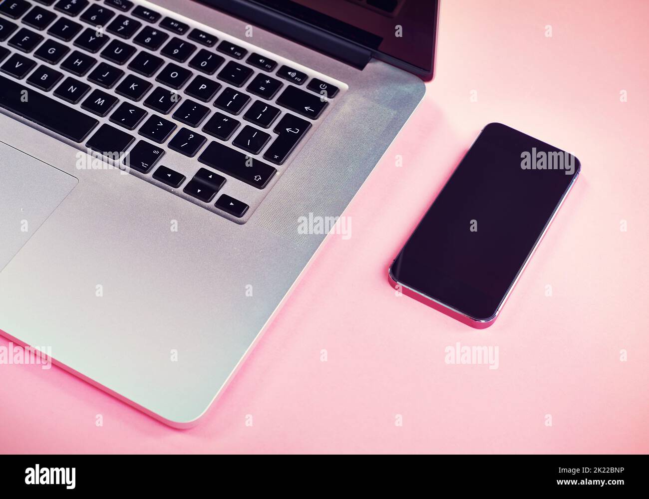 Bring your own device to the table. Studio shot of a laptop and smartphone on a pink background. Stock Photo