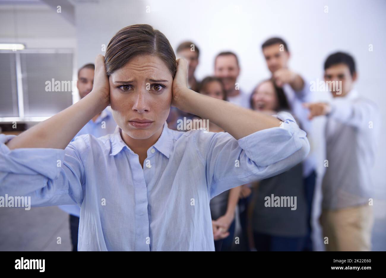 I cant hear you. a stressed young woman trying to block out her coworkers taunts. Stock Photo
