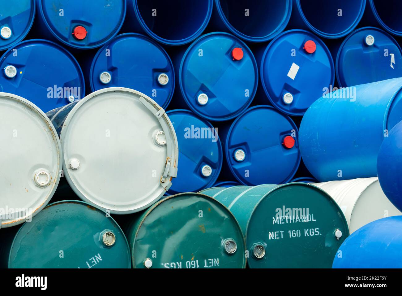 Old chemical barrels. Stack of blue methanol or methyl alcohol drum. Steel chemical tank. Toxic waste. Chemical barrel with toxic warning symbol. Stock Photo