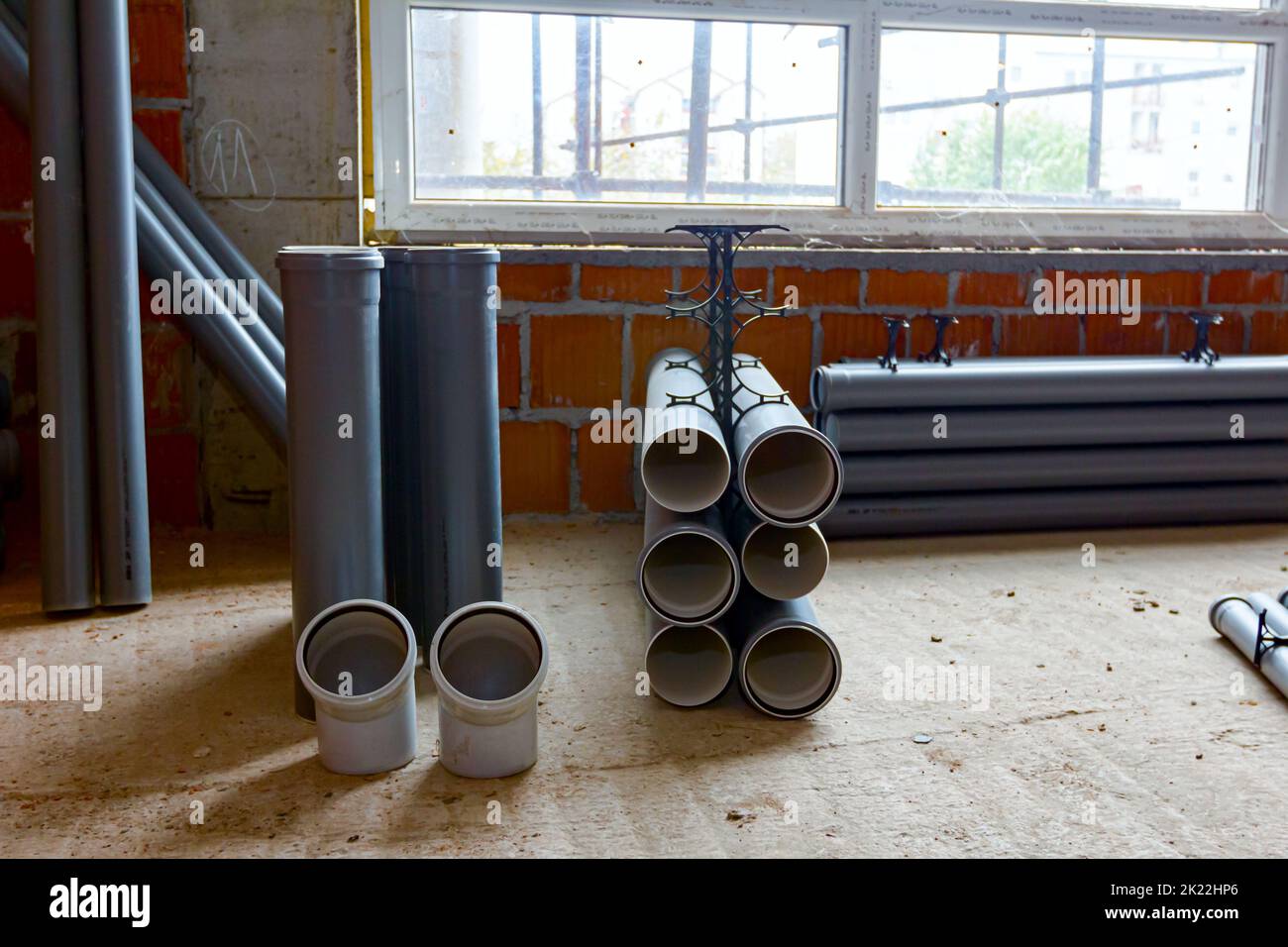 Arranged new grey plumbing sewer pipes are laid down on the floor