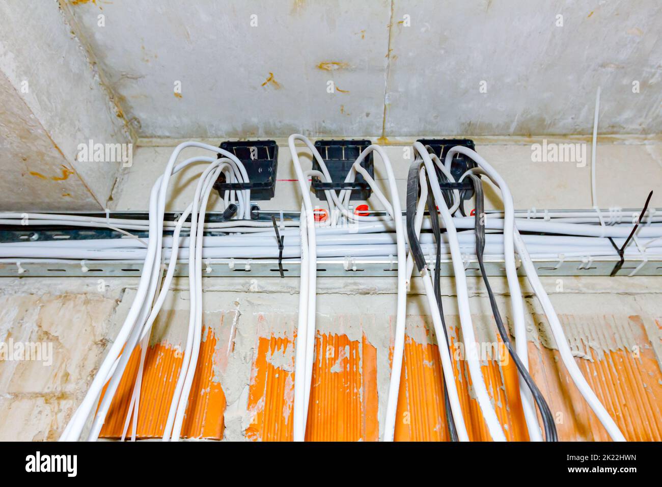 Cables are hanging from ceiling of building under construction, work in progress. Placement of