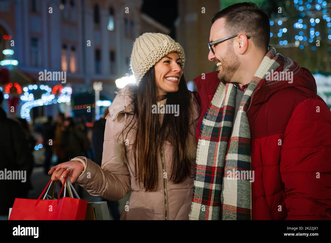 Cheerful happy couple doing Christmas shopping standing on decorated street. Sale people concept Stock Photo