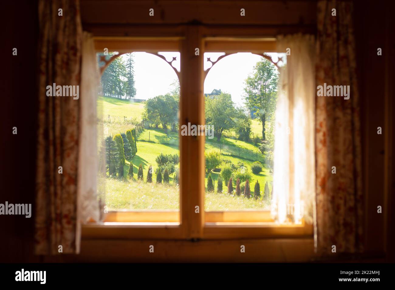 Front view of wooden window with curtains, sunny landscape rural view with trees and hill. Rustic holiday, digital detox Stock Photo