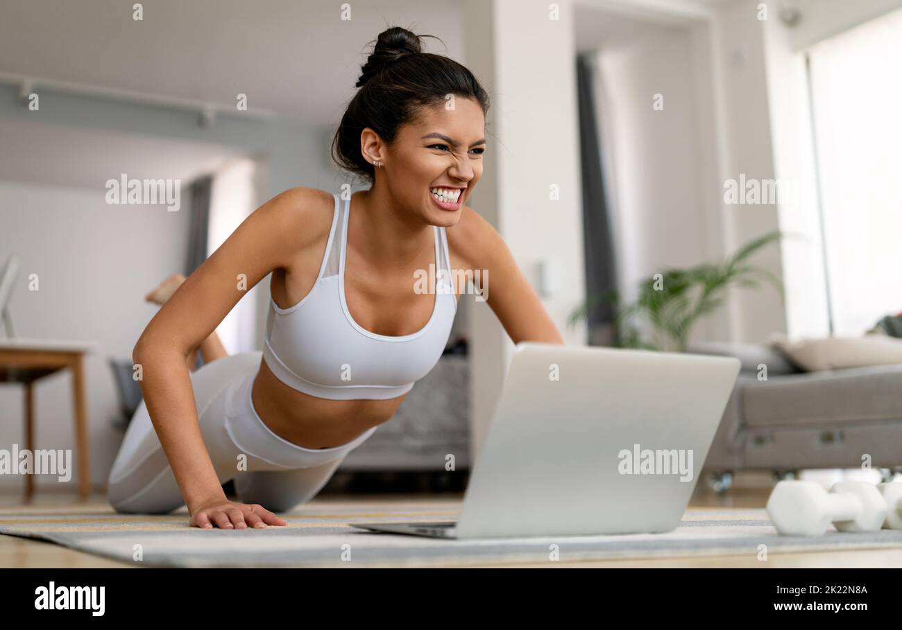 Beautiful fit woman exercise fitness at home instead of going to the gym. Stock Photo