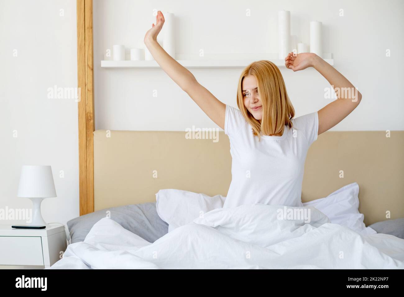 Good morning. Rise and shine. Healthy wellbeing. Sleep wellness. Fresh rested cheerful young woman stretching in soft bed white bedsheets blanket at c Stock Photo