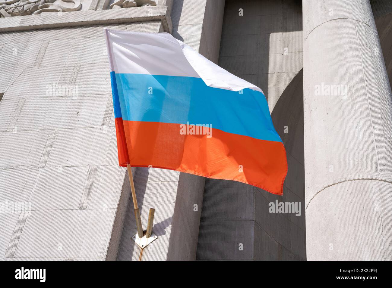 Russian flag. Russian flag displayed on a pole in front house. National flag russian federation is waving up to the house hanging from a pole on the front door of the building. Stock Photo