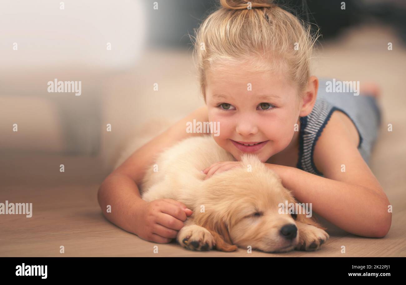 Snuggles and cuddles. An adorable little girl with her puppy at home. Stock Photo