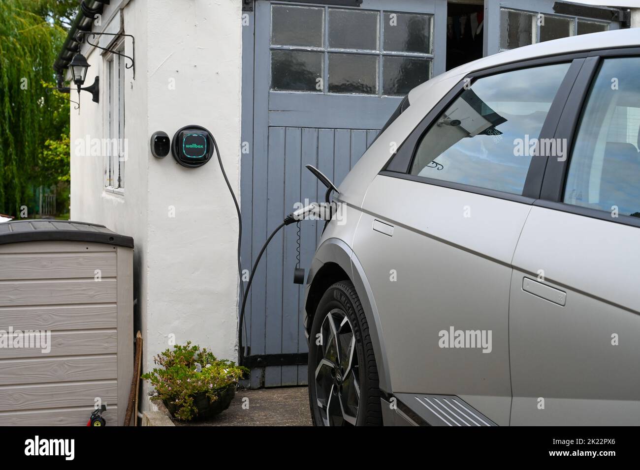 Hyundai Ioniq 5 charging at home, EV wall charger outside a rural garage wallbox charger Stock Photo