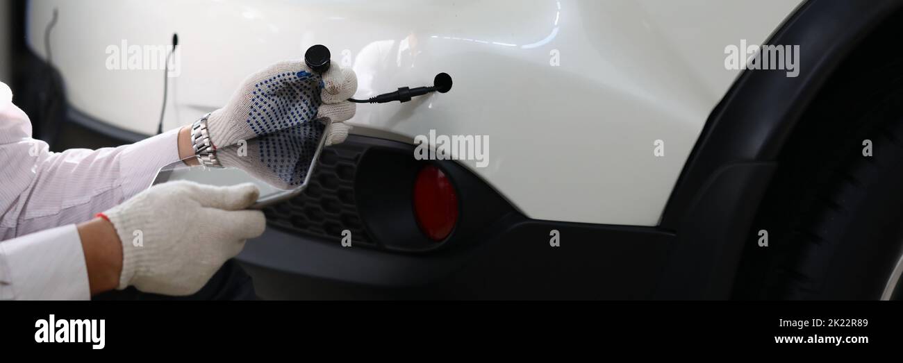 Mechanic installs parking sensors on car closeup Stock Photo