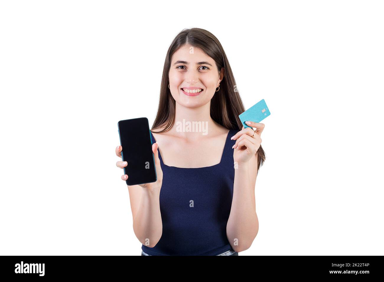 Positive young woman looking excited to camera showing her phone screen and holding a credit card in other hand, isolated on white background with cop Stock Photo