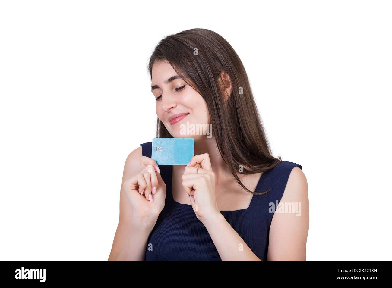Overjoyed young woman holding to chest her favorite credit card. Close up portrait of a dreamy girl with eyes closed wishing for sale and discounts is Stock Photo