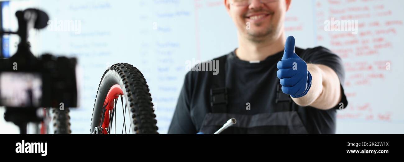 Bicycle repairman in workshop holding thumbs up Stock Photo