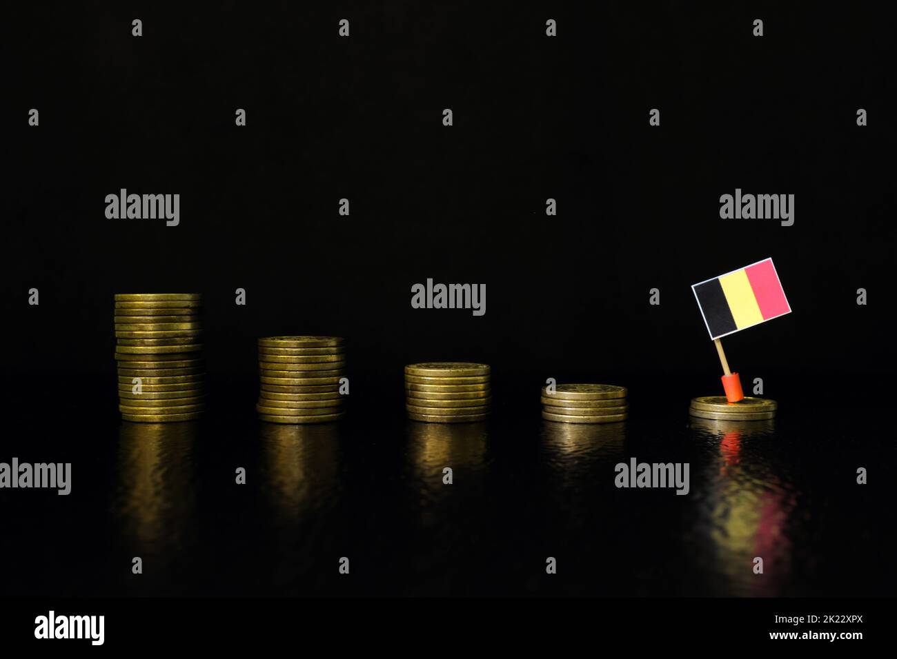 Belgium economic recession, financial crisis and currency depreciation concept. Belgian flag in decreasing stack of coins in dark black background. Stock Photo