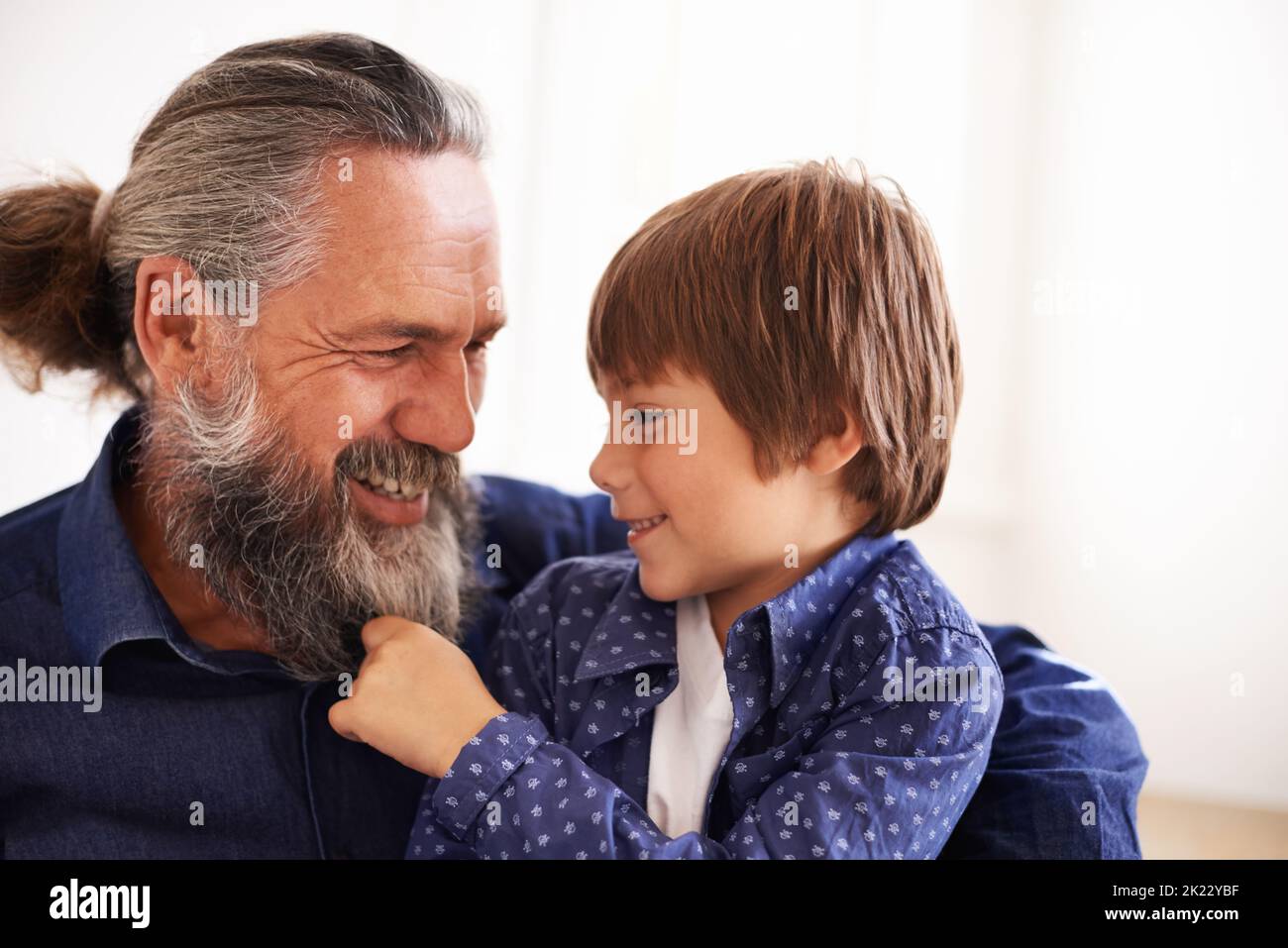 Grandpa are you Santa. a young boy playing with his grandfathers beard. Stock Photo