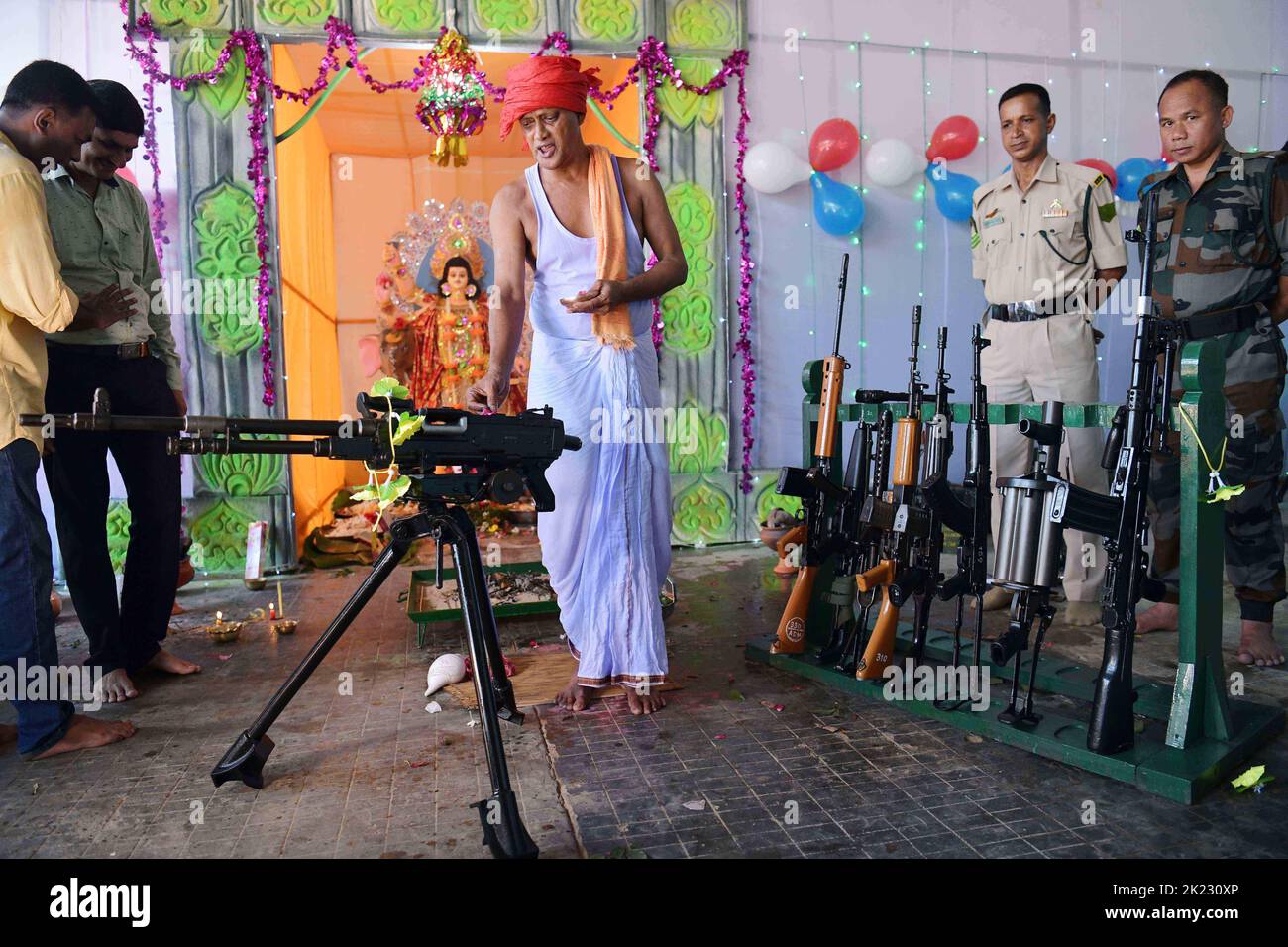 A priest blessing weapons belonging to TSR 2nd Battalion (Tripura State Rifles ) during the Vishwakarma Puja festival, a Hindu God, the divine architect, in the TSR camp on the outskirts of Agartala. Tripura, India. Stock Photo