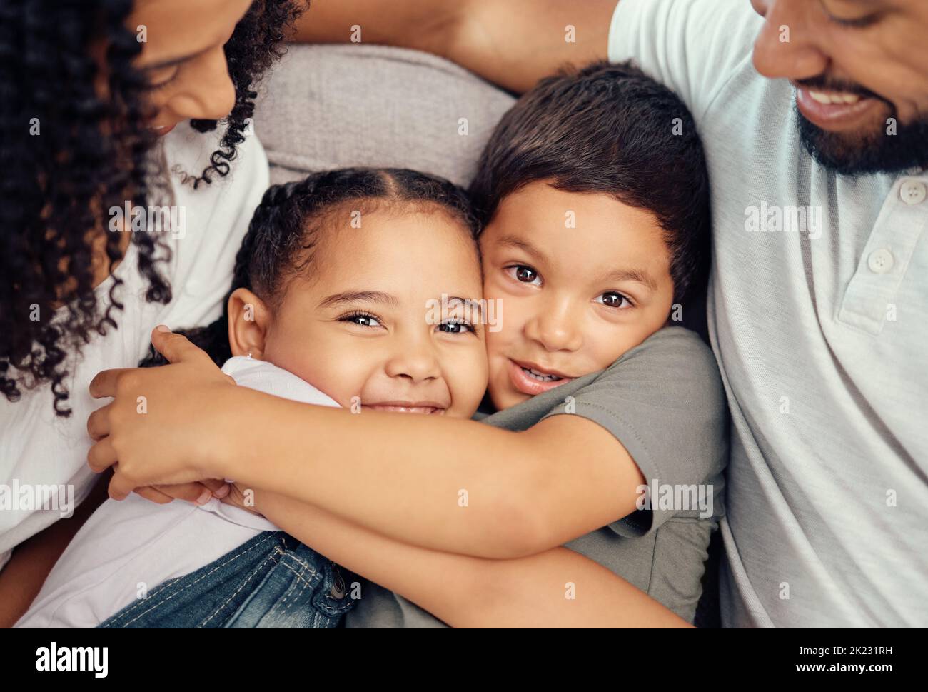 Portrait, happy family and children hug and bonding on a sofa, happy and relax with mother and father at home. Smile, relax and embracing kids Stock Photo