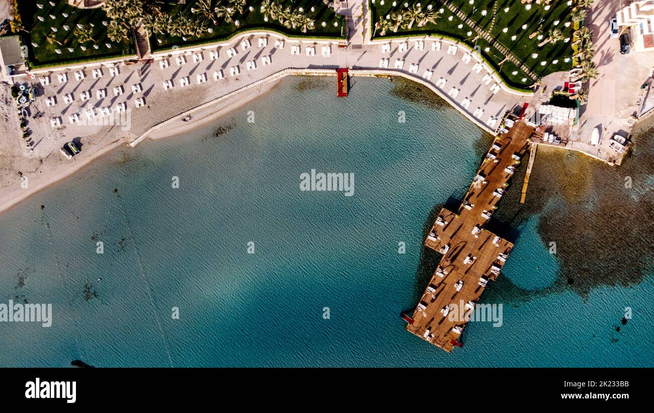 Aerial drone top view to the beach with white sand, pier with sunchairs and blue sea. Luxury summer vacation and resort. concept. Stock Photo