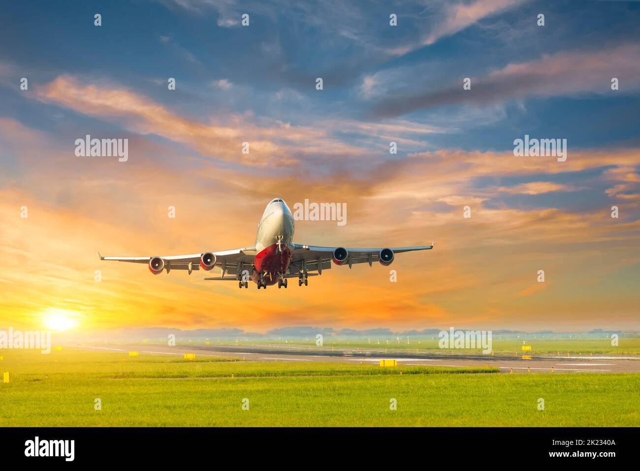 Airplane takes off during a beautiful sunset from the runway, against the backdrop of a beautiful sunset yellow sky Stock Photo