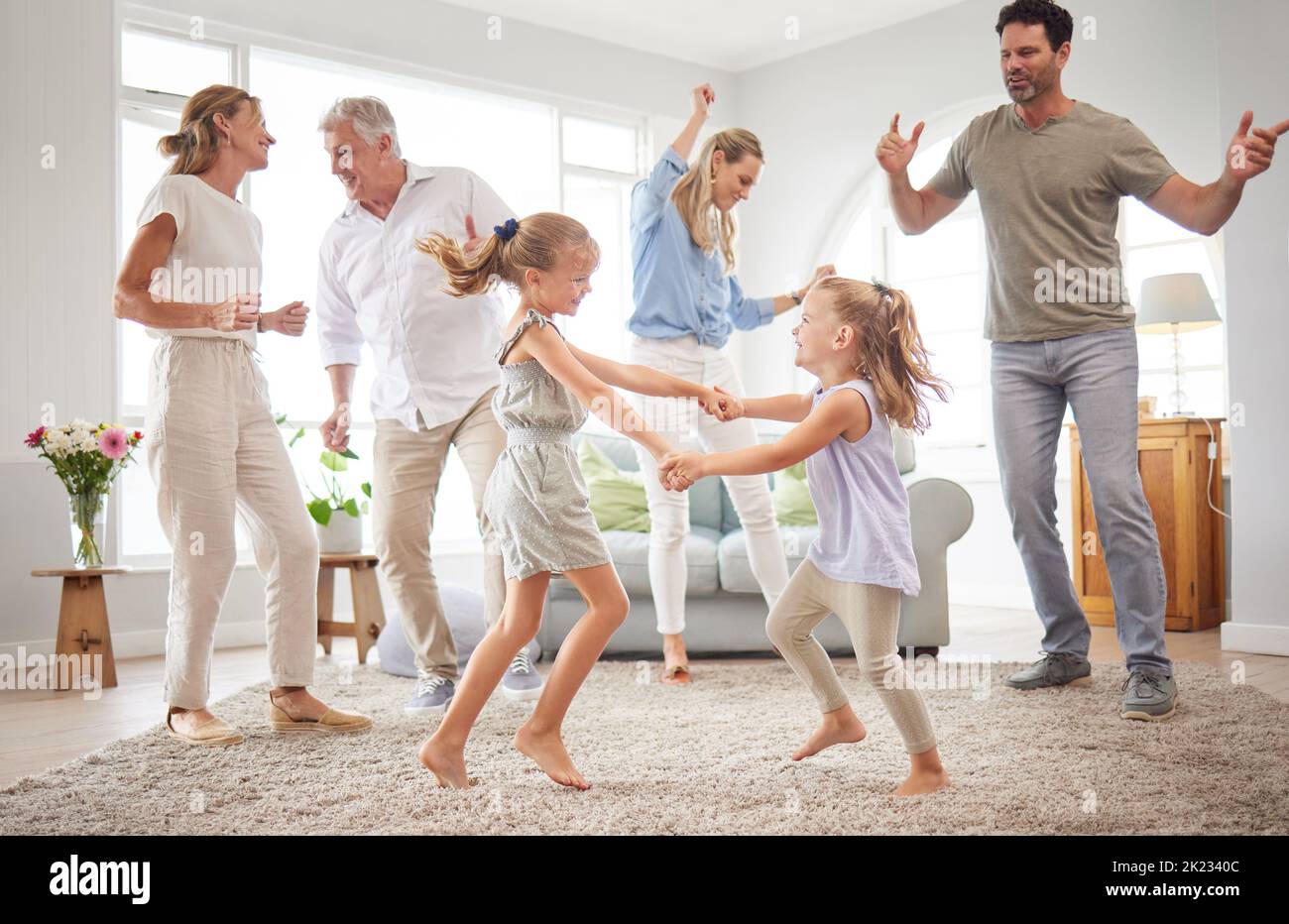 Happy, dance and love with big family in living room together for crazy, energy and excited. Lifestyle, freedom and celebration dancing at modern home Stock Photo